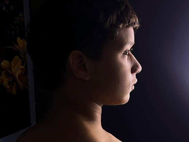 AlexDuMontt's profile shot shows short brown hair, a slightly turned-up nose, and a calm expression, illuminated by soft light from the right, with dark, shadowed background.