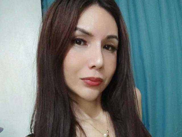 MissHotAyaLove with long brown hair, red lipstick, and subtle makeup, wearing a necklace, looking directly at the camera with a slight smile.