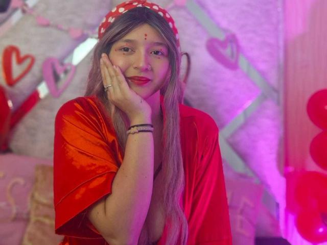 CandySwan with pink and gray hair, glittery butterfly and star face paint, nose ring, and pink lipstick, wearing a white halter top, showing off her cute face.