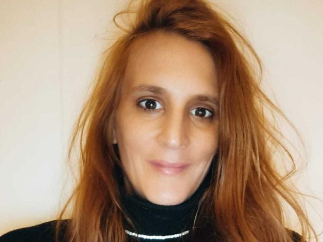 MadamHermosa ha i capelli biondo scuro, gli occhi marroni e un leggero sorriso. Indossa una maglia nera a collo alto con una striscia bianca. Le sue natiche non sono visibili..