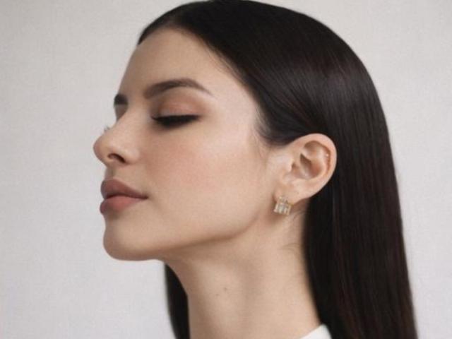 IsabellaJames has smooth, dark brown hair, closed eyes, subtle makeup, and a small, gold, diamond-studded earring in her right ear. Her face is turned slightly to the left.