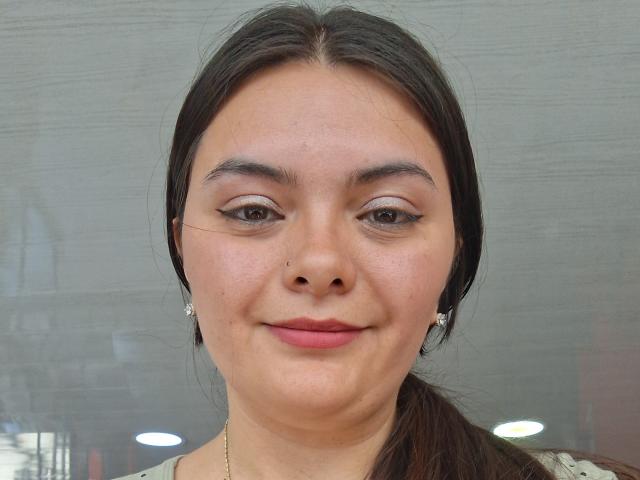 Katherin Latin ha gli occhi marroni, le sopracciglia scure e indossa orecchini di diamanti. Sorride con il rossetto rosa, ha un naso piccolo e i capelli castano scuro legati in una coda di cavallo..