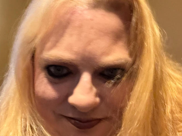 Cherish Williams a les cheveux blonds, un front légèrement ridé, du maquillage foncé pour les yeux et un sourire discret. Son nez est rose et elle regarde directement l'appareil photo..