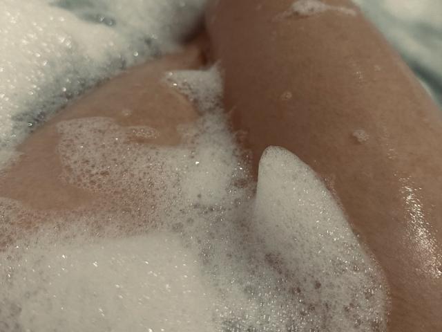 Diantrisy's ass and upper thigh in a bubble bath, with white soap suds covering her skin, her brown skin is visible in the lower right corner.