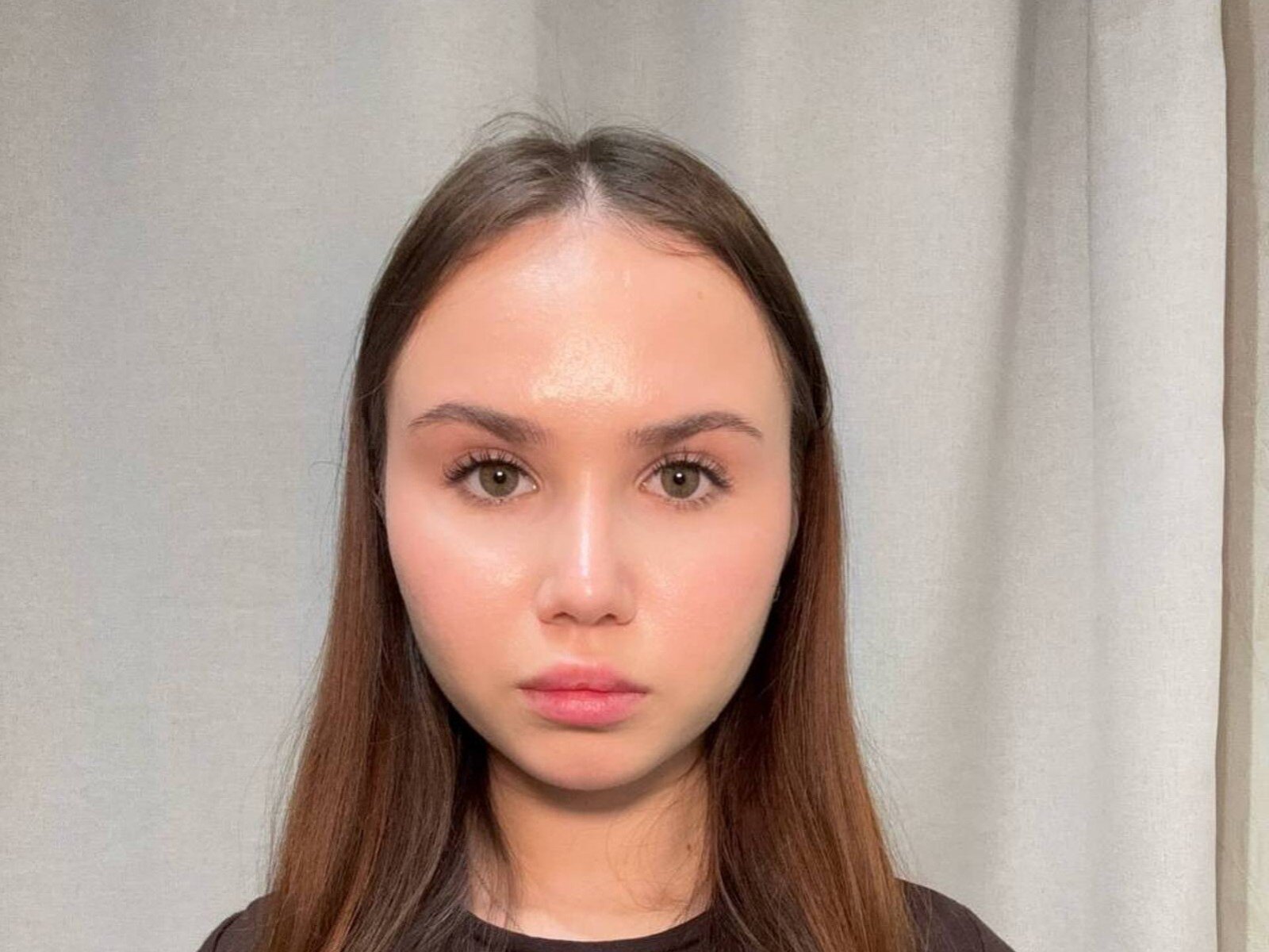 Denita Zahm tem cabelo castanho liso, olhos verdes e uma testa brilhante. Ela está vestindo uma blusa preta e tem uma expressão neutra. Suas nádegas não estão visíveis..