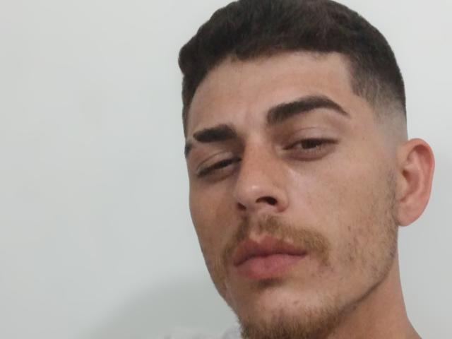 Gbsousa69 hat ein ernstes Gesicht, kurze, dunkelbraune Haare und einen kleinen Schnurrbart. Seine Augenbrauen sind dick und er blickt leicht zur Seite mit halb geschlossenen Augen..