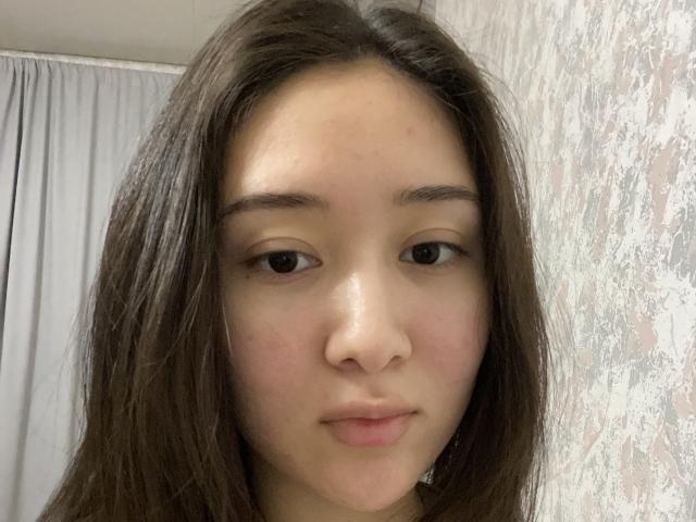 IzettaDingel has brown eyes, straight brown hair, and a light skin tone. She's looking at the camera with a slight smile, showing a small nose and full lips.