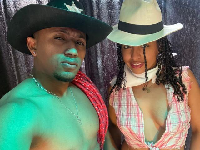 LilithAndAsmodeo with dark skin and short beard wears a black cowboy hat and red rope, shirtless. Beside her, LilithAndAsmodeo with curly hair, white hat, plaid top, and big tits.
