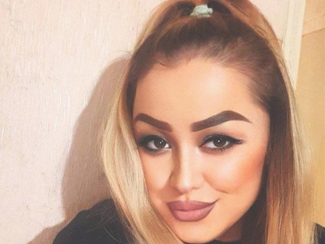 Airisha heeft blond haar in een staart, dikke donkere wenkbrauwen, grote bruine ogen en roze lippenstift. Haar make-up is opvallend met dramatische eyeliner. Ze glimlacht lichtjes..