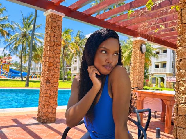 LipaSianax with dark skin and long black hair, wearing a blue tank top, leaning on a chair by a pool, gazing sideways with a seductive look, palm trees in background.