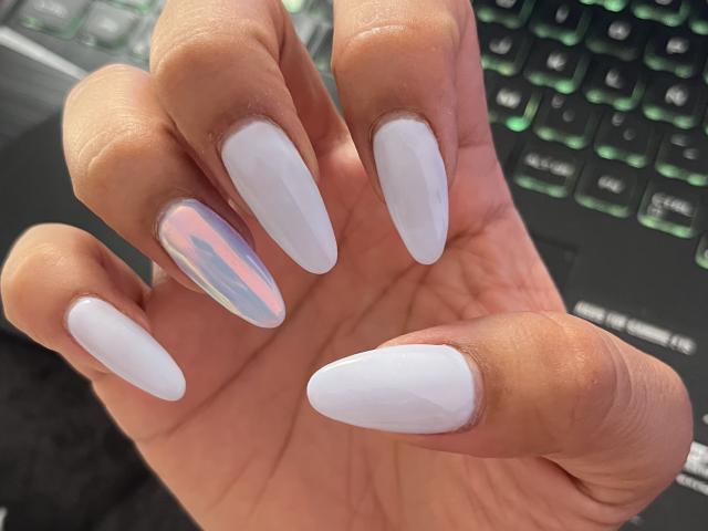 Nahaufnahme von Elizabeth Macys Hand mit langen, weißen, glänzenden Acrylnägeln, wobei ein Nagel einen pinkfarbenen und silbernen, irisierenden Farbton aufweist. Fertig. Hand auf einer schwarzen Tastatur mit grünen Tasten. Verdammt sexy..