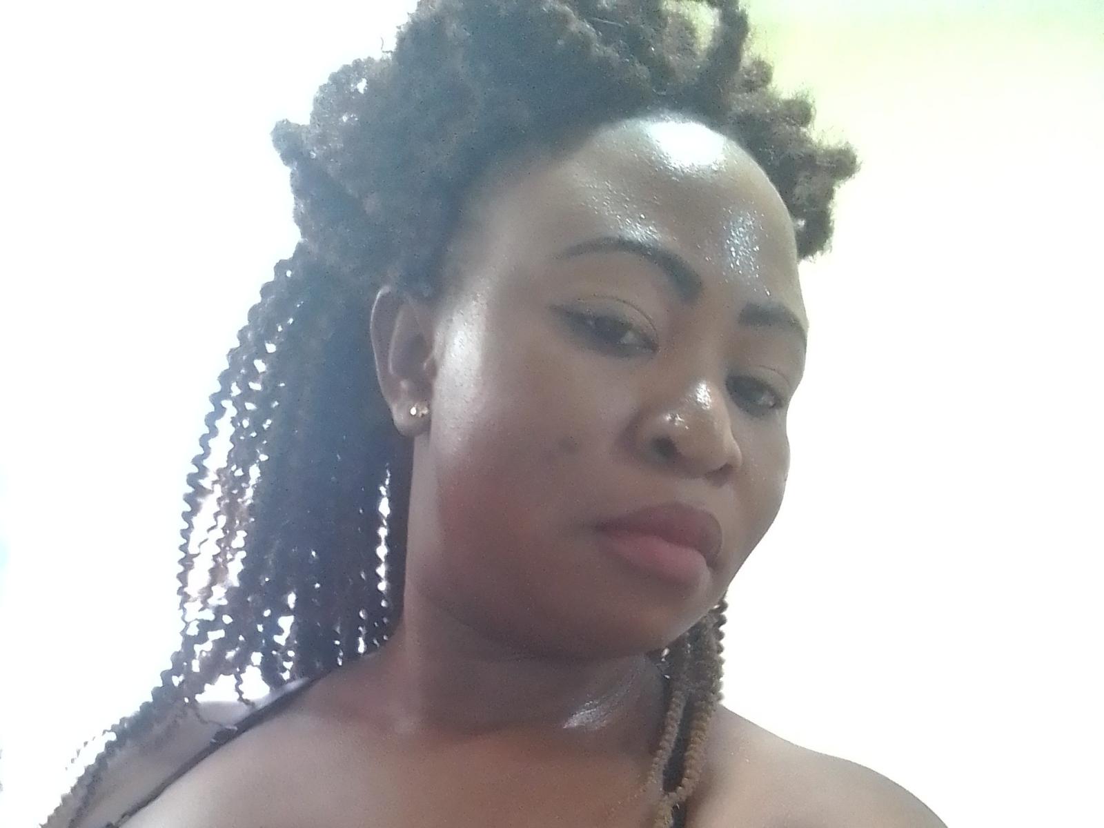 Lavisky001 a une peau noire brillante, des dreadlocks bouclés de couleur marron moyen, et porte un maquillage discret avec un rouge à lèvres rose. Elle regarde vers le bas avec une expression calme, montrant son petit nez..