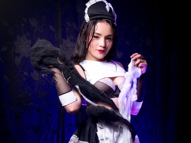 ViolettaMidnight in a black and white maid outfit, holding a black feathered fan, dark wet hair, intense gaze, red lipstick, black and white lace trim, dark background, sexy pose.