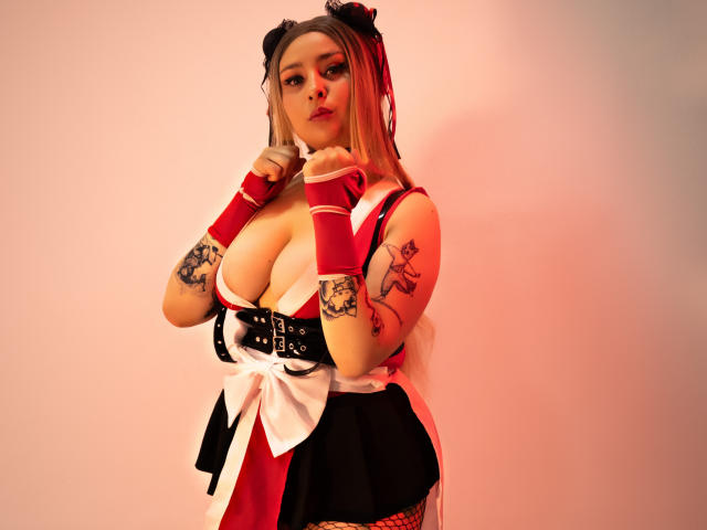 Digitale Kunst von DandelionQueen, mit üppiger Figur und großen Brüsten, in einem roten und weißen Outfit, schwarzen Spitzenhandschuhen und Fischernetzstrümpfen. Strümpfe und ein Katzenohrband, sie posiert verführerisch mit einem Finger an den Lippen..