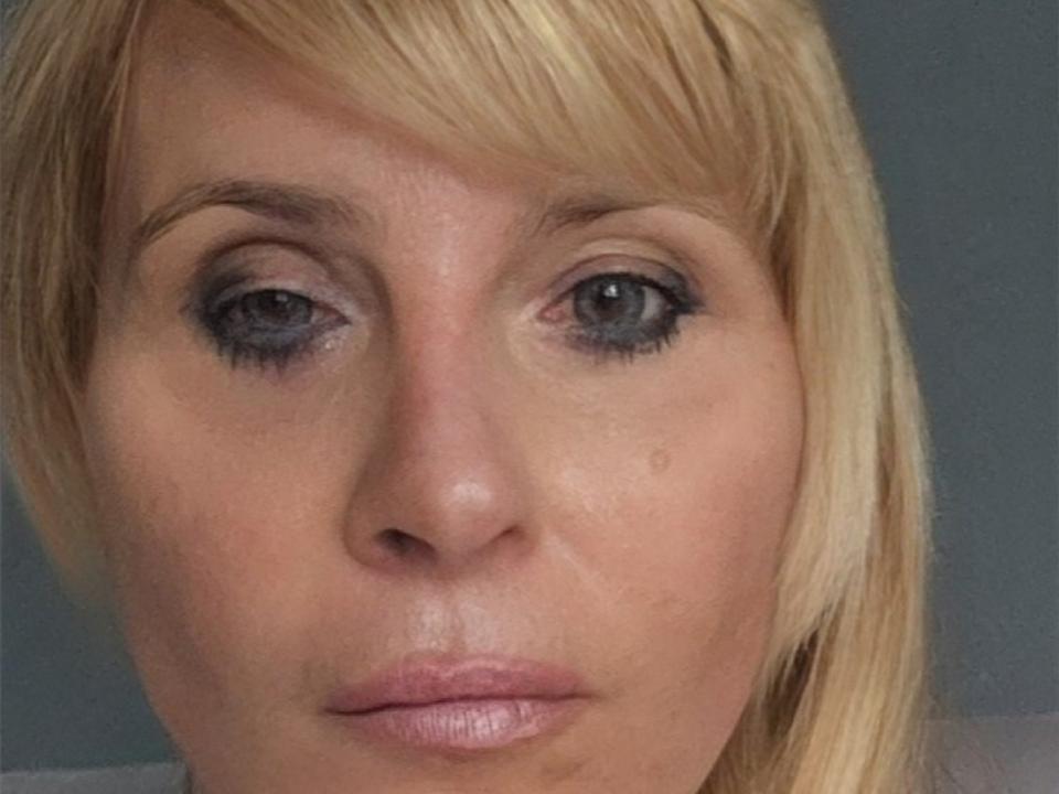 Fotografia ravvicinata di VanessaLibertine, una donna bionda con occhi azzurri, un pesante trucco di eyeliner nero, labbra rosa leggermente dischiuse. espressione neutra, luce soffusa sul viso, texture della pelle delicata, leggera ombra sotto gli occhi.