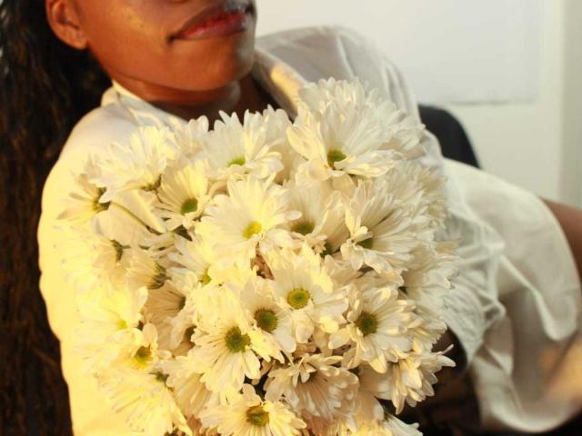 Vsakurap holds a large bouquet of white daisies close to their chest, wearing a white shirt. The flowers are bright and detailed, with Vsakurap's lower face partially visible. Fucking sexy.