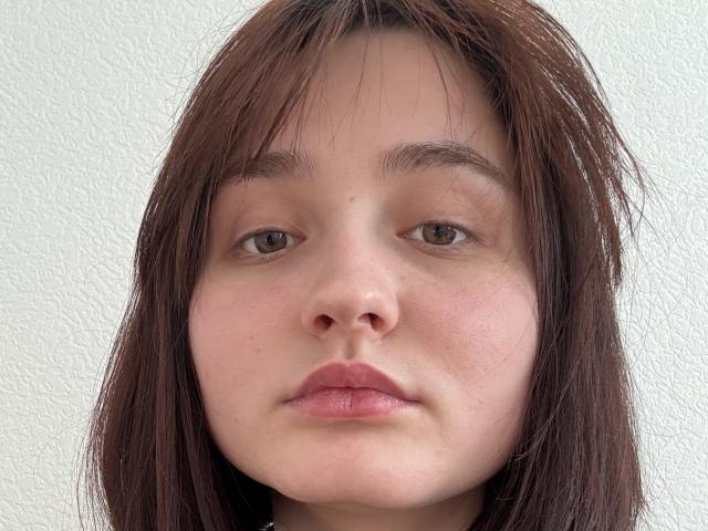 Nahaufnahme von Gricelda Lydick mit heller Haut, braunen Augen und glattem, braunem Haar. Sie blickt direkt in die Kamera und hat einen neutralen Gesichtsausdruck. Ihre Lippen sind leicht geöffnet, was Anspannung zeigt..