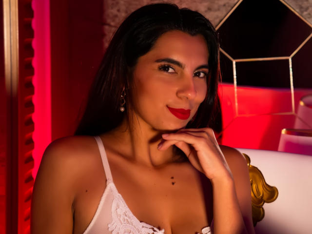 CarlaTorres, sexy brunette woman with long hair, wearing white lace bra, red lipstick, smirking, hand near face, red and black background, hexagonal mirror, soft lighting, sultry expression, seductive pose.