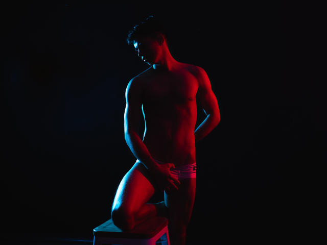 Silhouette von CodyPipper, muskulös, stehend, trägt enge Unterwäsche, Hand auf dem Penis, beleuchtet von blauem und rotem Licht. an einer Kiste anlehnen, dunkler Hintergrund, schattiges Gesicht, intensive sexuelle Spannung, dramatische Beleuchtung.