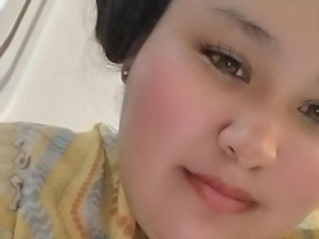 Close-up of CattaleyaBohorquez, focusing on her face and upper body. She has light skin, dark eyes, and pink cheeks, wearing a yellow and brown patterned top. She's smiling slightly. Her nose is pierced.