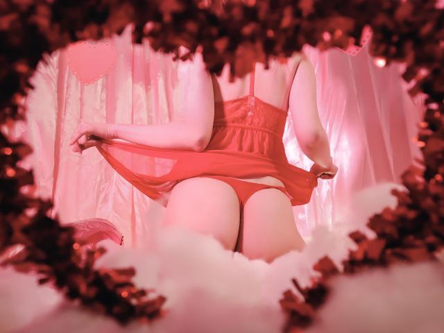 Obra de arte digital de AmbeerWood deitada de costas, com as pernas abertas, exibindo nádegas grandes e arredondadas em uma calcinha vermelha. Nuvens rosa, brilhantes e fofas emolduram a imagem. A tensão sexual é intensa..