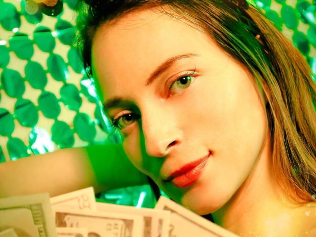 Photo en gros plan d'AmbeerWood avec une expression séduisante, un éclairage vert et jaune, des cheveux bruns et des lèvres rouges. Tenant de l'argent devant un fond vert, avec un effet bokeh. Putain, c'est sexy..