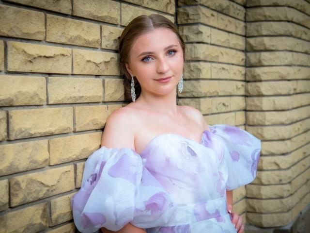 SamuelaBella, mit heller Haut, blauen Augen und braunen Haaren, trägt ein weißes, schulterfreies Kleid mit Puffärmeln und steht. vor einer Ziegelwand, leichtes Lächeln, Ohrringe, weiches Licht, sexy.