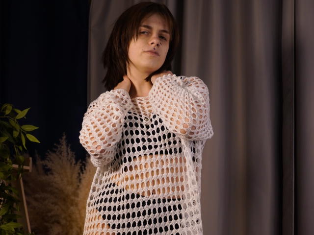 DejaSorley, com cabelo preto na altura dos ombros, vestindo uma blusa branca de malha transparente, com as mãos atrás do pescoço, expressão séria. expressão, fundo com pouca luz, com cortina e planta. Muito sexy, mamilos à mostra, pose confiante..