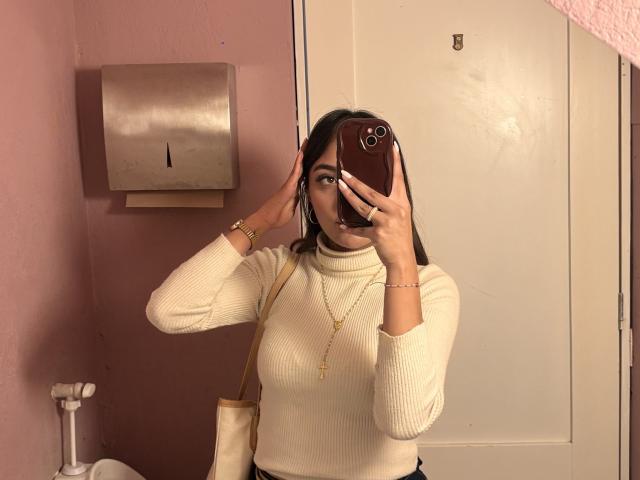 DianaFernandezz taking a mirror selfie in a bathroom, wearing a white ribbed turtleneck, gold chain, and bracelet. She's holding a phone with one hand, covering her face. Fucking hot.