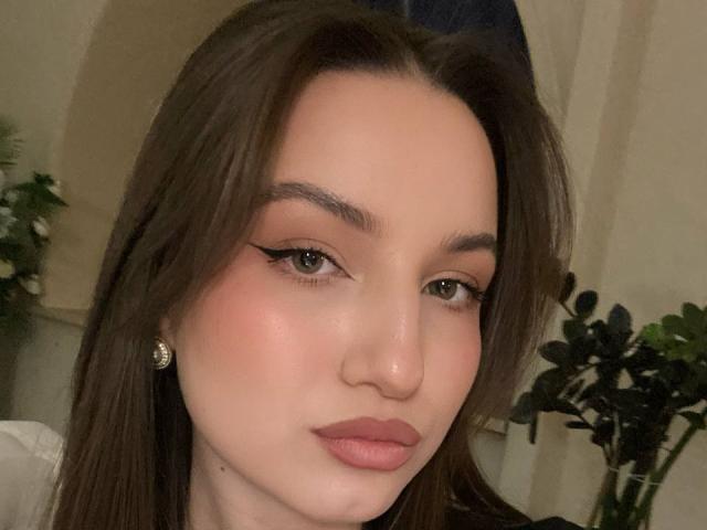 Primo piano di MargertLewi, una giovane donna con la pelle chiara, i capelli castano scuro e le labbra rosa. Ha l'eyeliner nero, un piccolo piercing al naso e indossa degli orecchini. Uno sguardo incredibilmente attraente e intenso..