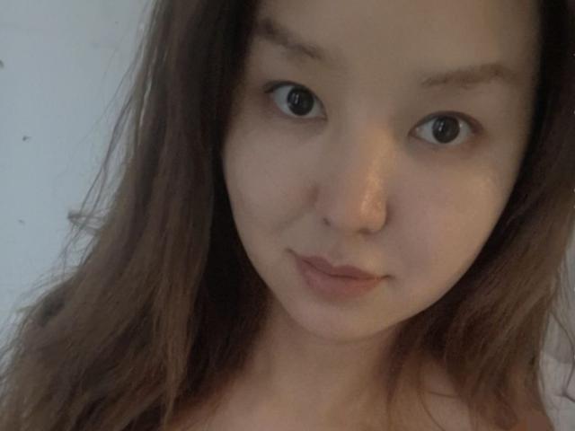 Close-up photo of MilenaAiymaa with large blue eyes, light skin, and brown hair. She has a slight smile and a nose piercing, looking directly at the camera. Fucking cute, innocent vibe.