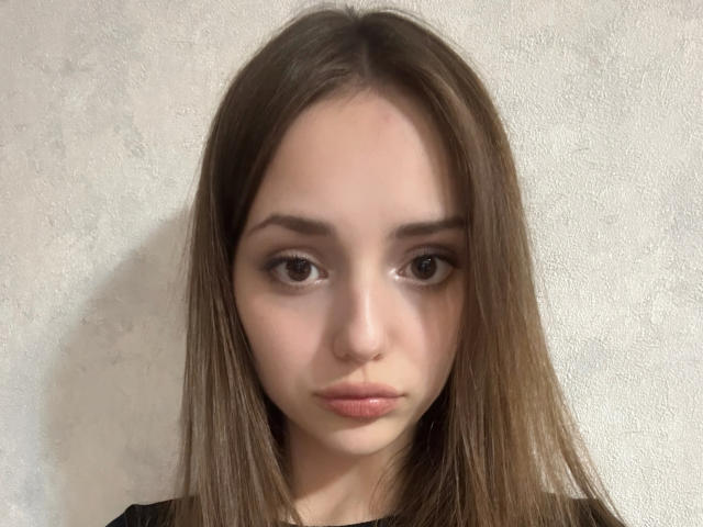 Foto van Treva Giumarro met lang bruin haar, bleke huid en bruine ogen, die recht in de camera kijkt. Neutrale uitdrukking.
zacht licht accentueert haar gezicht, waardoor een licht schaduwrijk effect ontstaat..