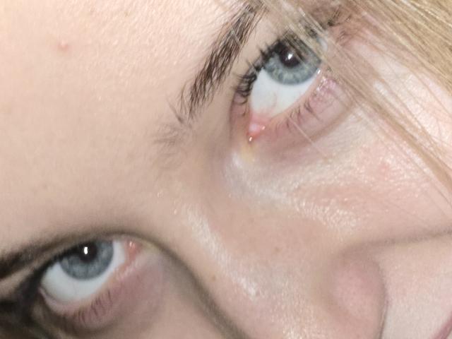 Close-up foto van het gezicht van DiedraBloschichak, met de nadruk op haar blauwe ogen en licht open lippen. Haar blonde haar is gedeeltelijk zichtbaar, met een lichte huid en subtiele oogmake-up. Extreem intense blik.