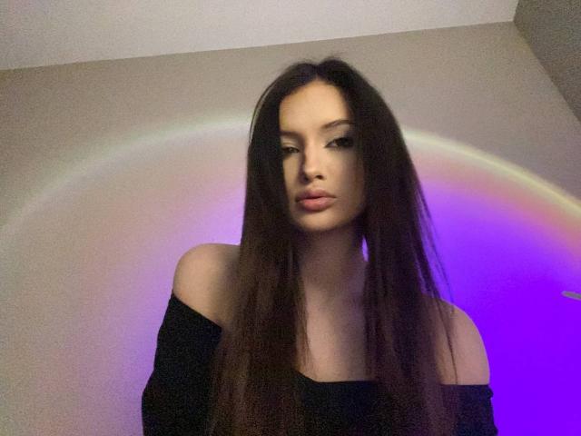 Marchelle Berrien, capelli lunghi e neri, top nero con spalline scoperte, espressione seria, luce arcobaleno soffusa sullo sfondo, tonalità viola-blu. lucentezza, trucco leggero, fisico slanciato, aspetto sensuale, fotografia, moderno, casual, bordi leggermente sfocati.