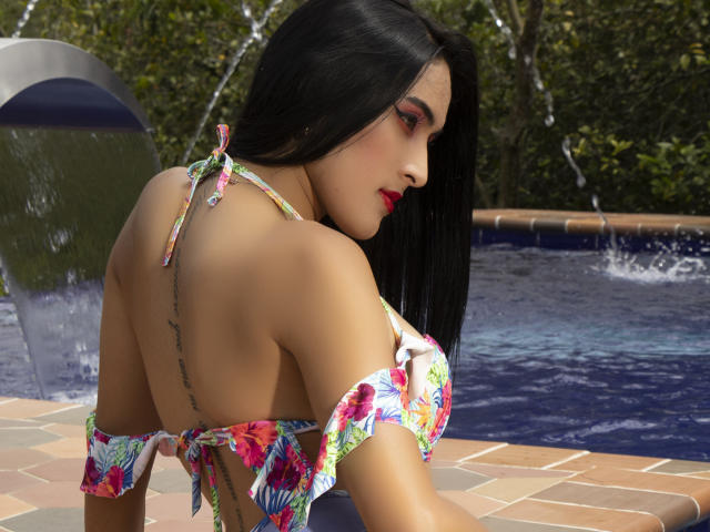 Obra de arte digital de EstrellaHarryson, una mujer de cabello oscuro con lápiz labial rojo, parte superior de bikini con estampado floral, tatuaje en la espalda, inclinada. borde de la piscina, gotas de agua en su piel, insinuaciones sexuales, colores vibrantes, entorno exterior soleado..