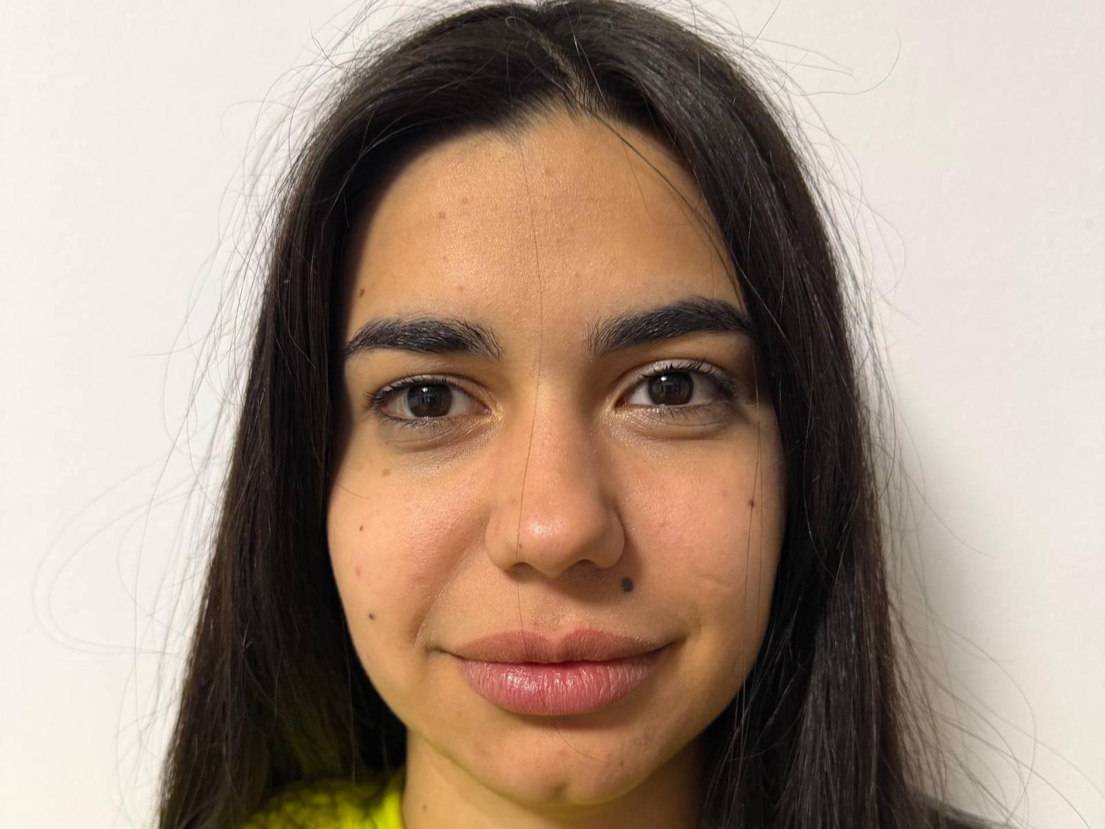 Photographie en gros plan de CharmyMariya, avec de longs cheveux noirs, des yeux marrons et un léger sourire. Sa peau est légèrement texturée, avec des pores visibles, et elle a une petite tache de naissance sur sa joue gauche. Ses lèvres sont pulpeuses et légèrement brillantes..