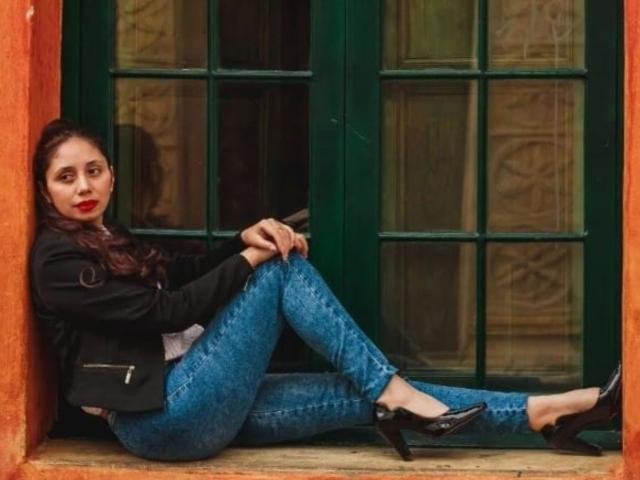 StephanieSun sits in a window, legs crossed, wearing blue jeans and black heels. She has red lipstick and dark hair, leaning against the green paneled window. Fucking sexy, relaxed pose.