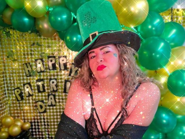 AdrianaPrettie, in un seducente abito di San Valentino. L'outfit per San Patrizio, con un cappello verde e una camicetta di pizzo nero, circondato da palloncini verdi e dorati, che lampeggiano. scintille, e "Buon compleanno, Patr.". Segno del "giorno"..