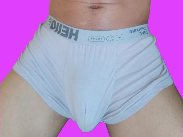 Photo en gros plan de la taille et de l'entrejambe de BlackBanana69, portant un slip moulant blanc "Diesel" avec un renflement visible, aspect doux. tissu, légers plis, sur fond rose vif, soulignant une tension érotique..