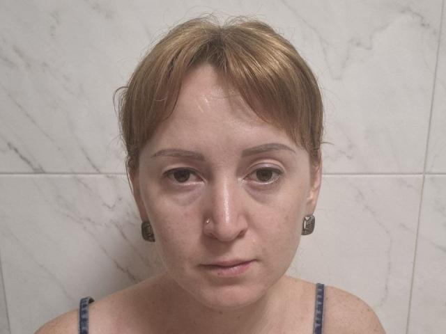 Tamariza ha i capelli corti e castani, la pelle umida e un'espressione neutra. Indossa degli orecchini neri e una maglietta a righe blu, con un piercing al naso ben visibile. Lo sfondo è composto da piastrelle di marmo bianco..