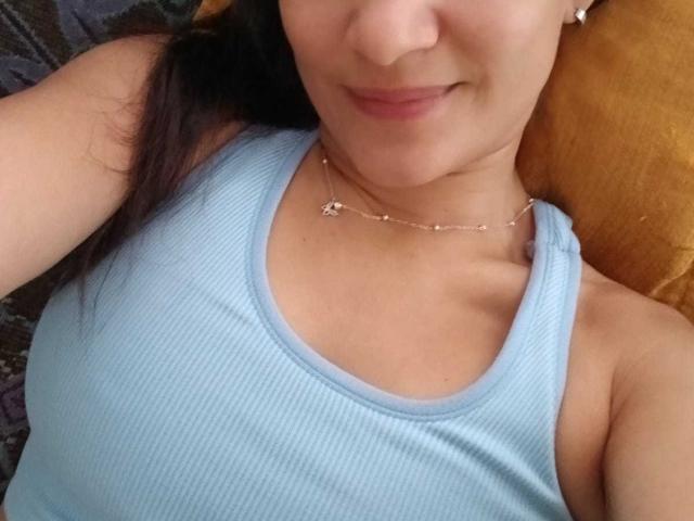 Gros plan de SolaraDubois, portant un débardeur bleu clair à rayures, qui met en valeur sa clavicule et un collier délicat. Son visage est partiellement visible, ses lèvres légèrement courbées dans un sourire discret. Extrêmement sexy.