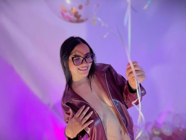 MiiaPalmer, vestida con una chaqueta de cuero negro, abierta para revelar el pecho desnudo, sosteniendo un hilo brillante, sonriendo y con gafas. Encendido, luz púrpura y azul neón en el fondo. Muy atractivo..