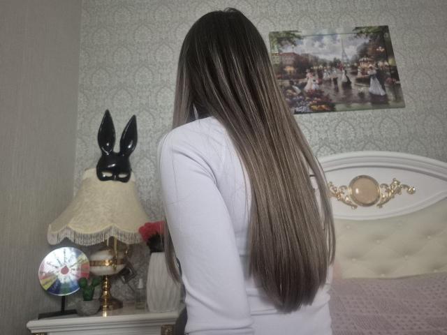 ZoieHurt, facing away, long straight brown hair, white top, standing in bedroom. Black bunny lamp, white lampshade, reflective ball, ornate headboard, framed photo on patterned wallpaper. Fucking sexy vibe.