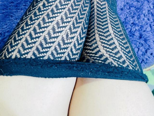 Primer plano de los glúteos de Cincia69, con ropa interior de encaje negro y un estampado en zigzag, las piernas ligeramente separadas, mostrando la piel pálida. Fondo azul con apariencia de pelaje, enfoque en la textura del encaje, tensión sexual, provocativo..