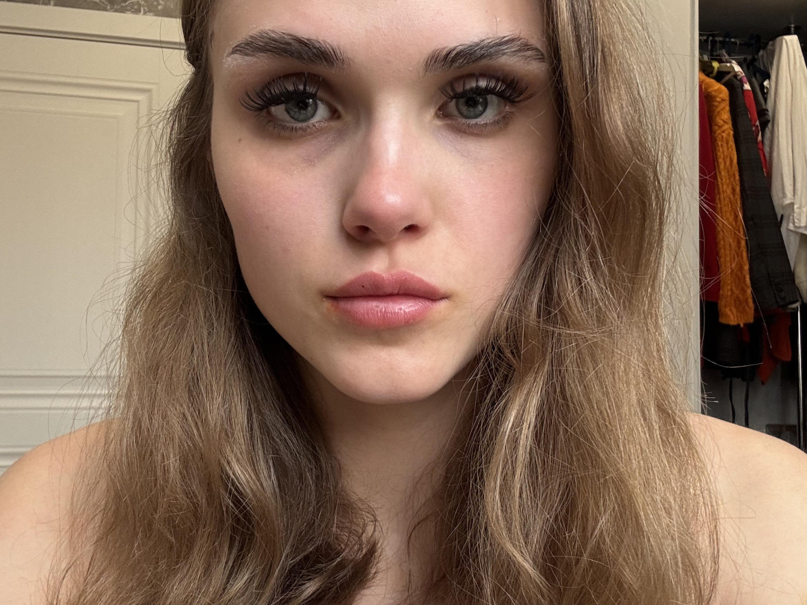 Close-up of JayePalin, a young woman with pale skin, blue eyes, and wavy brown hair. She gazes directly at the camera with a neutral expression, slight sexual tension evident.