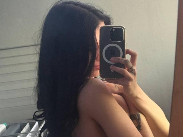 ShylaCatillo, with long black hair, takes a mirror selfie with a smartphone, partially covering her bare breasts with her hand. Her phone has a circular ring on the back. Fucking sexy.
