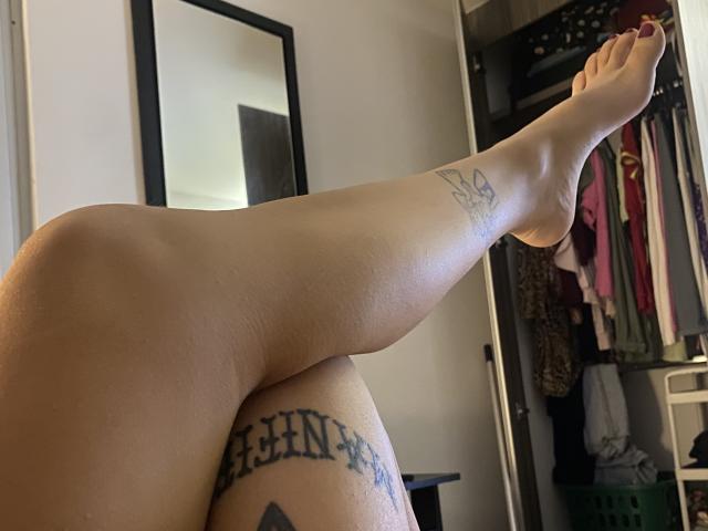 Fotografía de primer plano de la parte inferior del cuerpo de IsabellaPalacio, que muestra su pierna derecha levantada, con un tatuaje en el muslo y el pie. Tatuaje visible en la pantorrilla, pie apuntando hacia arriba, armario en el fondo. Increíblemente atractivo/a..