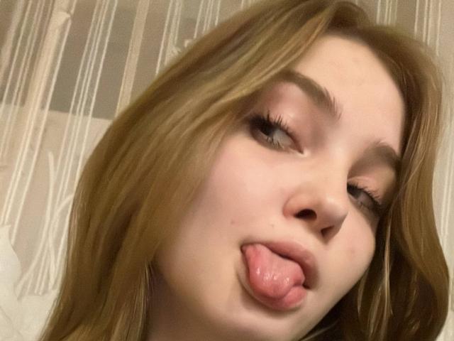 Fotografía de primer plano de Calista Swiatek, sacando la lengua con una expresión juguetona. Su cabello castaño claro está despeinado, tiene los ojos medio cerrados y tiene la piel clara. El enfoque está en su rostro..