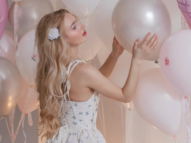 Flora Davis, com longos cabelos loiros ondulados, vestido branco com estampas florais e um acessório de cabelo com flores brancas, segurando balões brancos, lábios... cabelo dividido, batom vermelho, tensão sexual, iluminação suave, pele clara, balões brancos e rosa.