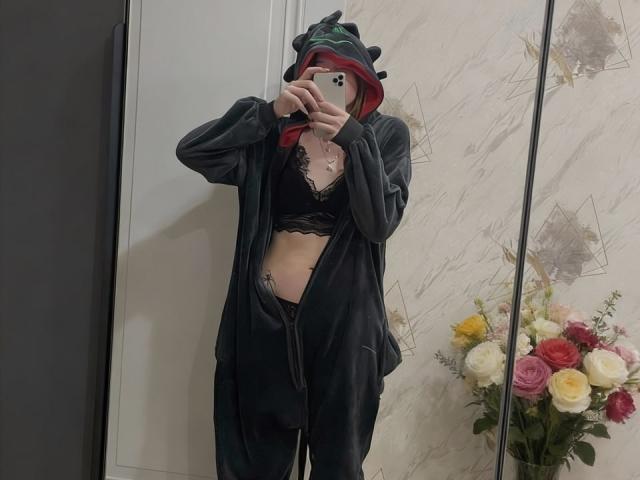 VeolaVanhoecke se toma un selfie frente al espejo, vistiendo una sudadera negra sin cerrar, con un gorro verde y rojo, un sujetador de encaje negro y pantalones negros, de pie cerca de un ramo de flores de colores. Increíblemente atractivo/a..